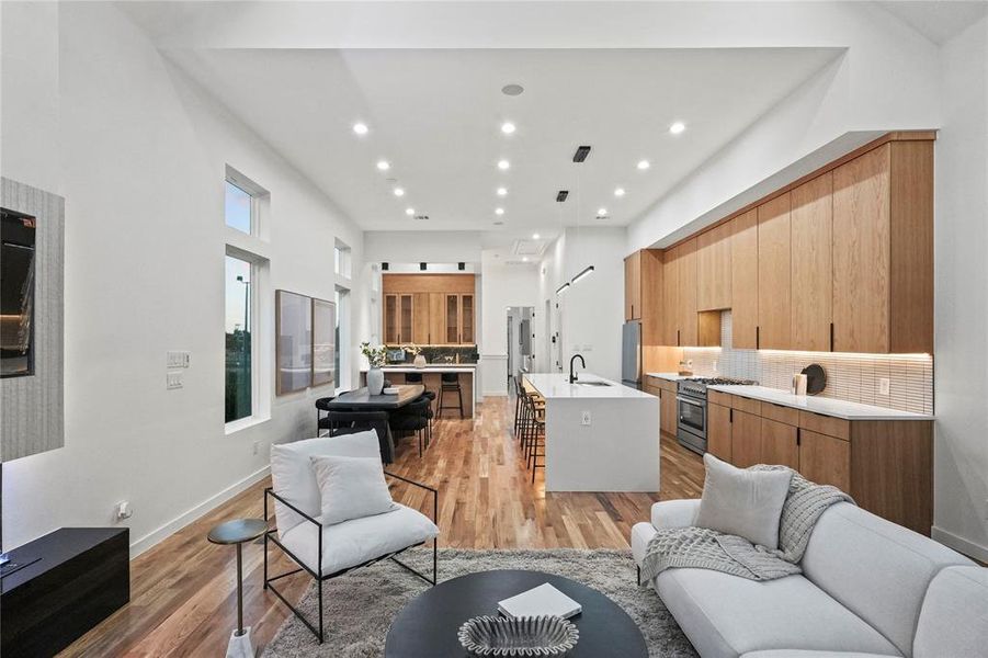 Living room featuring light wood-type flooring, a towering ceiling, and sink