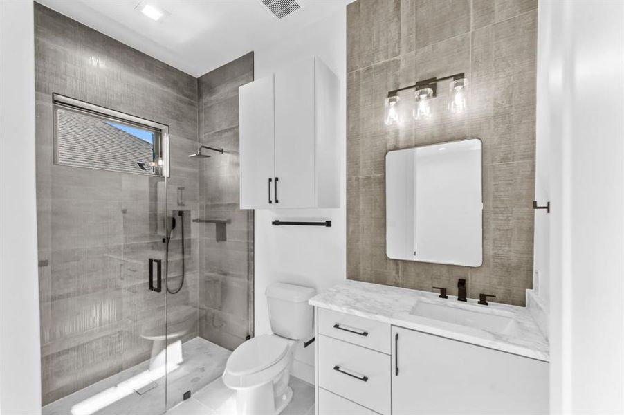 Bathroom featuring walk in shower, vanity, and toilet