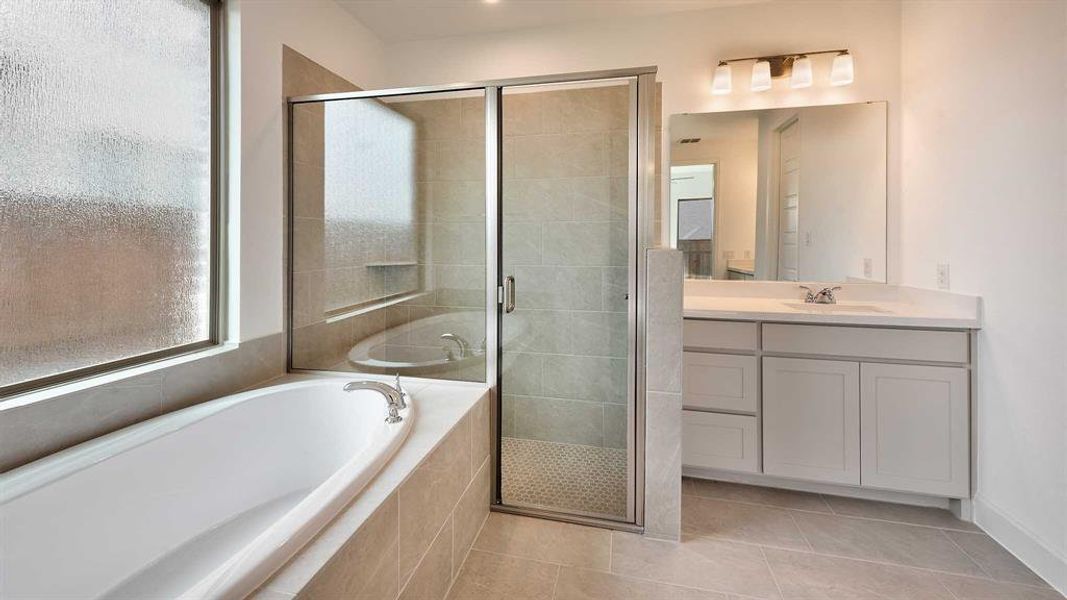 Bathroom with vanity, tile patterned flooring, and shower with separate bathtub