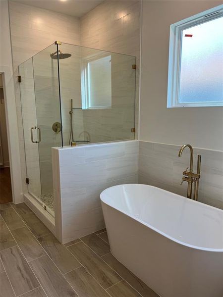 Bathroom featuring separate shower and tub and tile walls