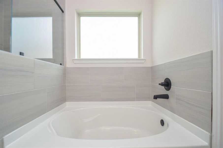 Unwind in the elegant soaking tub, surrounded by sophisticated tile work and complemented by a large window that fills the space with natural light. This relaxing sanctuary invites you to indulge in a spa-like experience from the comfort of home.