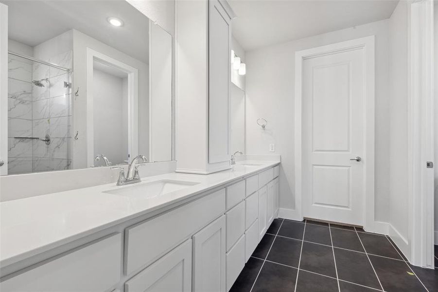 Bathroom featuring a tile shower, tile flooring, and dual bowl vanity