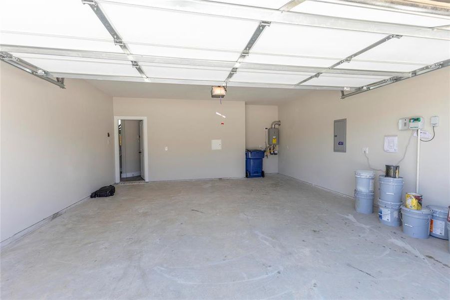 Garage with electric panel, tankless water heater, and a garage door opener