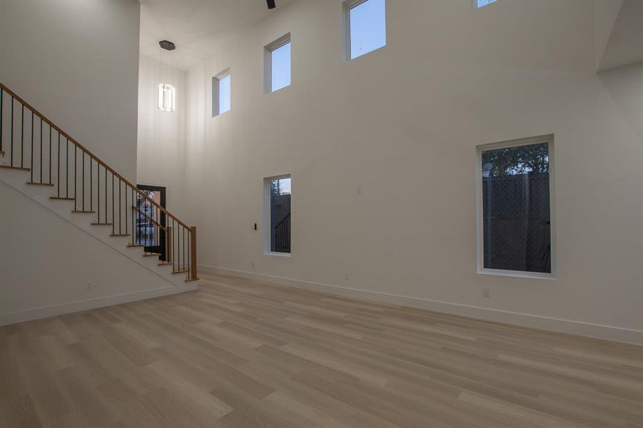 Unfurnished living room with a towering ceiling and light hardwood / wood-style flooring