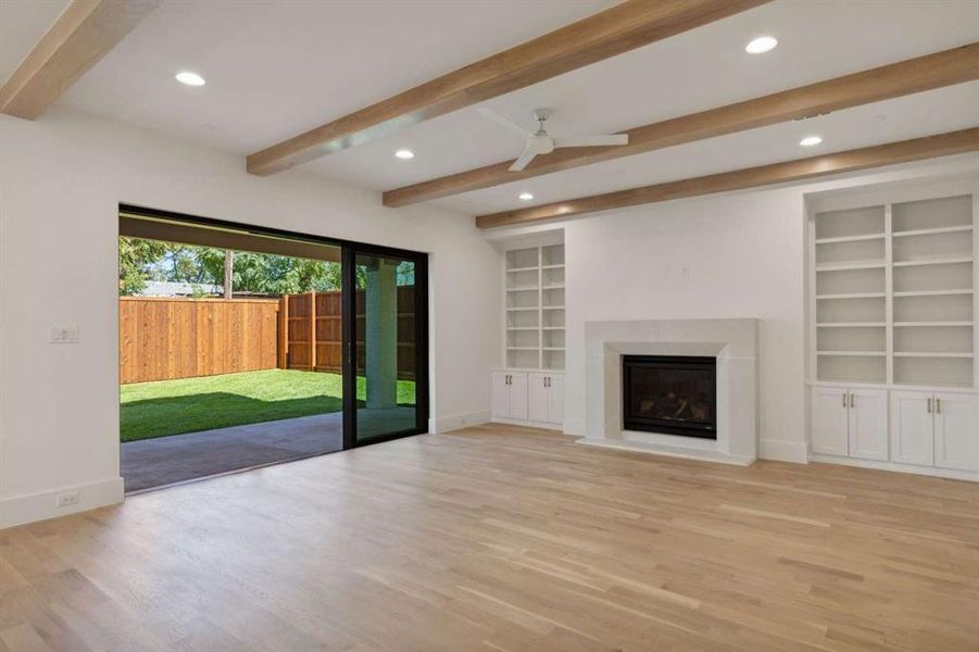 Unfurnished living room featuring light hardwood / wood-style floors, ceiling fan, and beamed ceiling