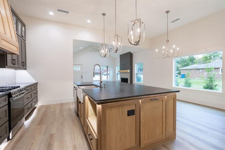 Kitchen with lofted ceiling, a center island with sink, pendant lighting, and appliances with stainless steel finishes