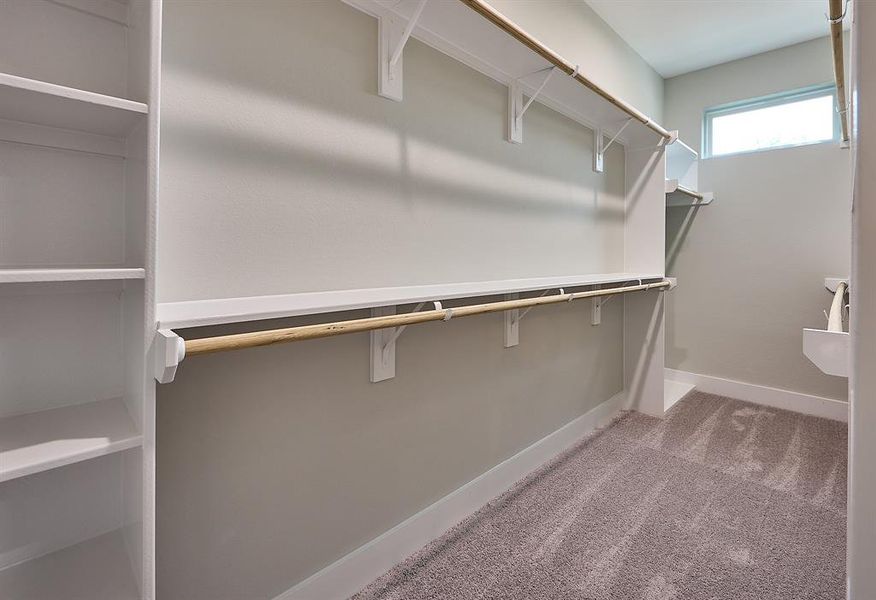 Primary bedroom walk-in closet offers plenty of shelving and clothing rack space.
