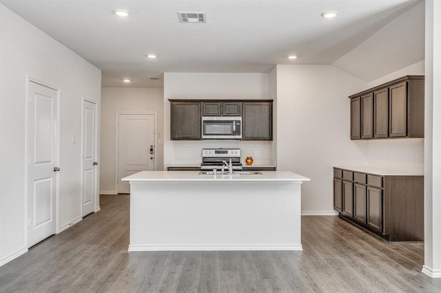 Kitchen featuring an island with sink, dark brown cabinets, light hardwood / wood-style flooring, and stainless steel appliances