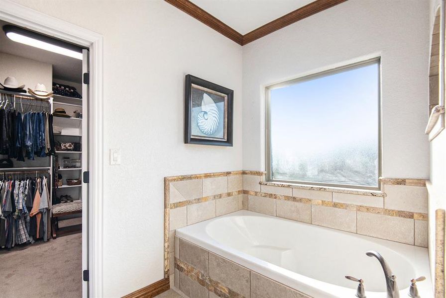 Bathroom with crown molding and tiled tub