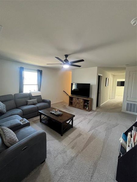 Carpeted living room with ceiling fan