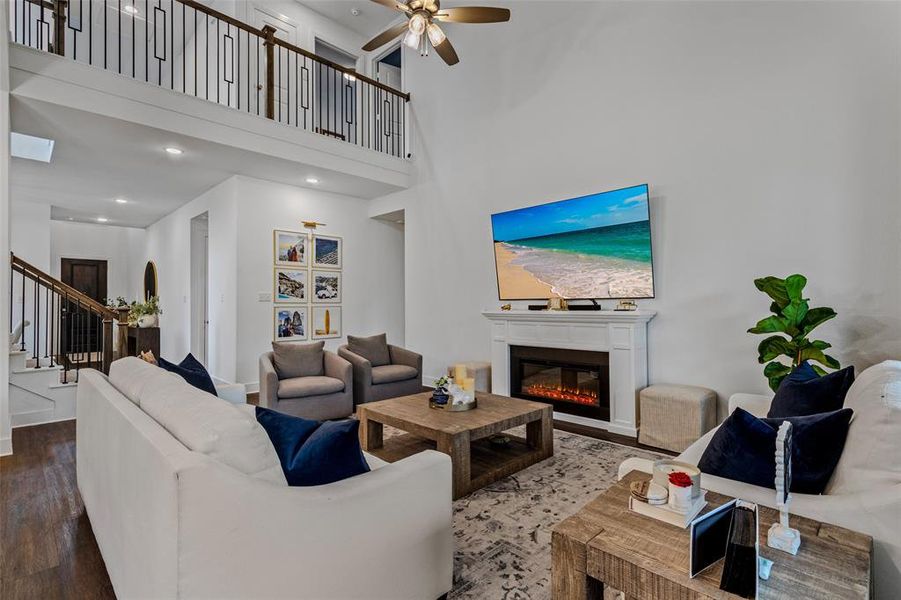 Living room with a high ceiling, hardwood / wood-style flooring, and ceiling fan