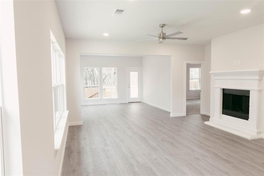Unfurnished living room with a wealth of natural light, ceiling fan, and light wood-type flooring