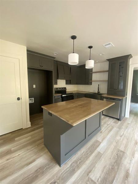 Kitchen featuring dishwasher, light hardwood / wood-style flooring, black stove, and a kitchen island