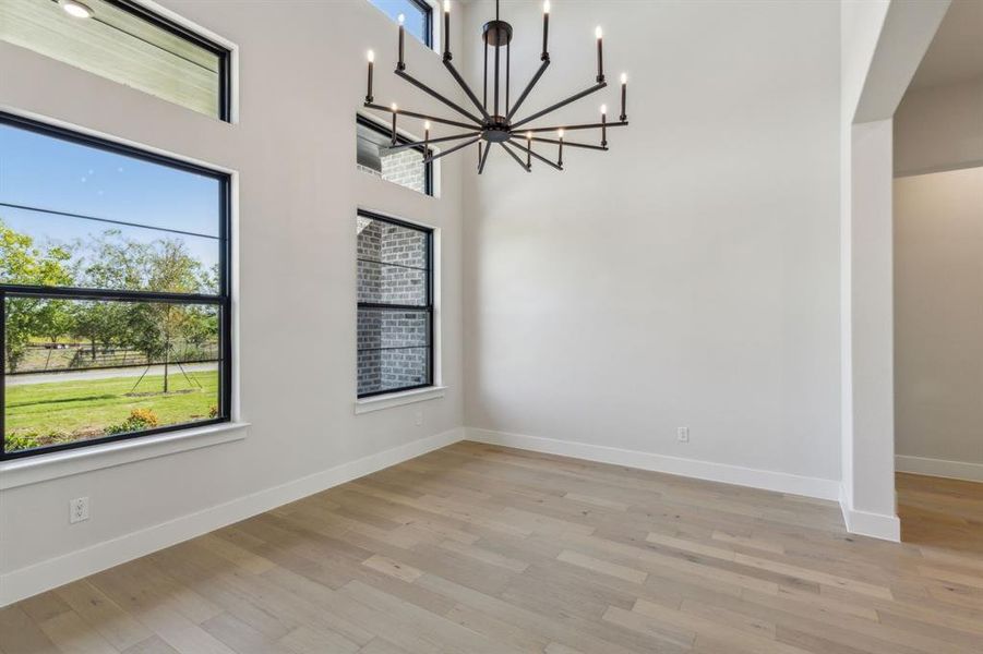 Spare room featuring a notable chandelier, light hardwood / wood-style floors, and a wealth of natural light