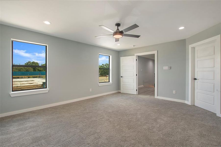 Unfurnished bedroom with light colored carpet and ceiling fan