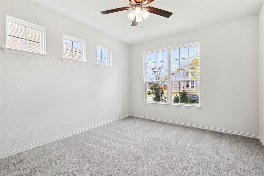 Carpeted spare room featuring a wealth of natural light and ceiling fan