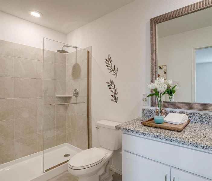 Bathroom featuring tiled shower, toilet, and oversized vanity