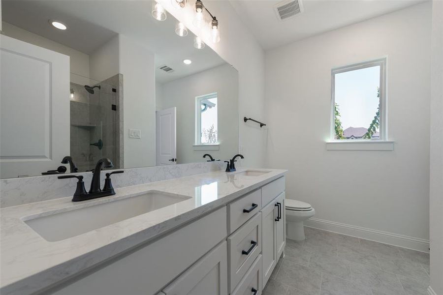 Bathroom featuring dual vanity, tile patterned floors, and toilet