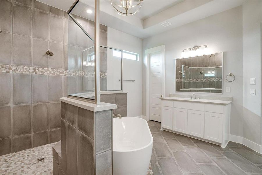 Bathroom featuring plus walk in shower, tile flooring, a tray ceiling, and vanity