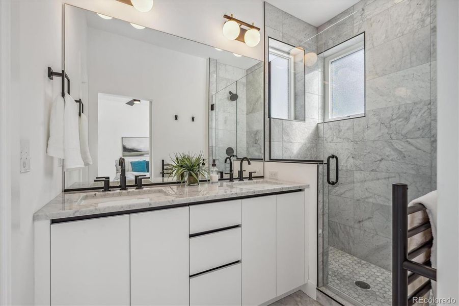 Primary Bathroom Boasting a Double Vanity, Heated Towel Rack, Barn Door Entry Plus Modern Tile, Finishes and Fixtures.