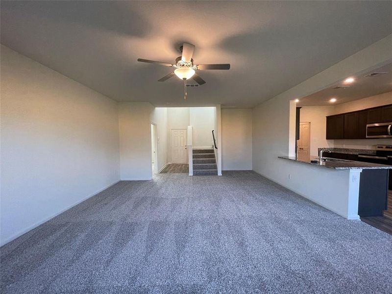 Unfurnished living room with carpet and ceiling fan