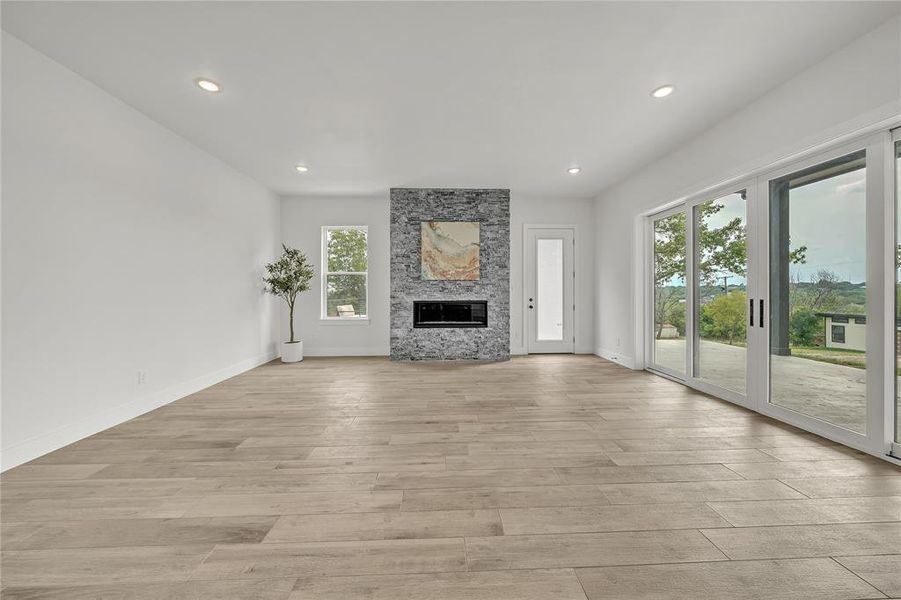 Unfurnished living room with a large fireplace, a healthy amount of sunlight, and light wood-type flooring