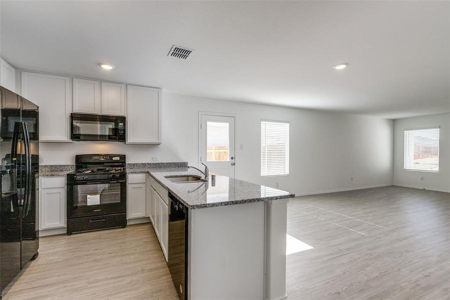 Kitchen featuring kitchen peninsula, light hardwood / wood-style floors, a wealth of natural light, and black appliances