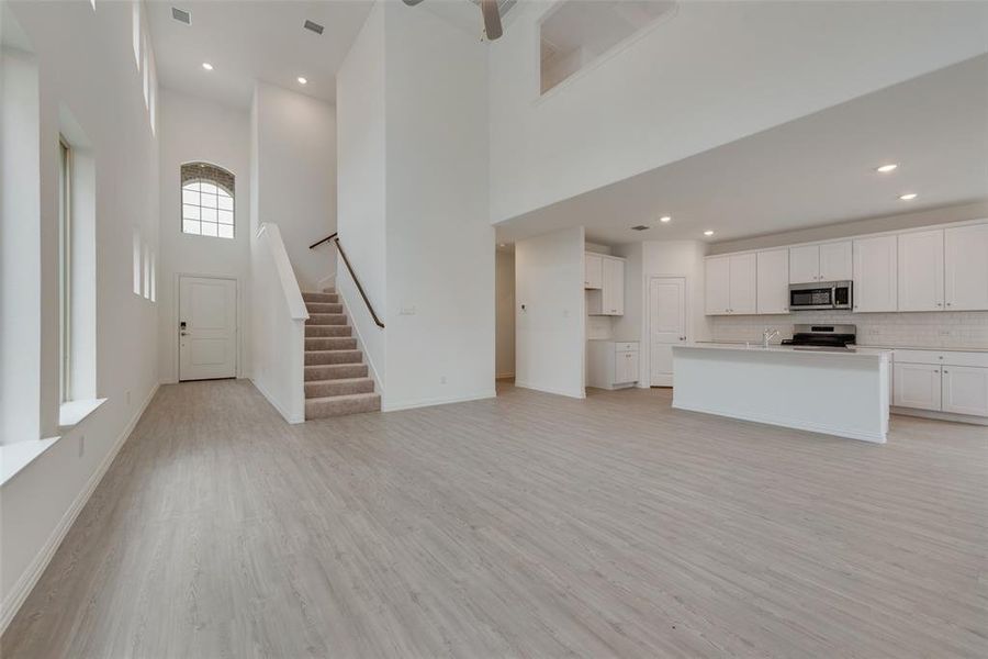 Unfurnished living room featuring sink, light hardwood / wood-style flooring, and a high ceiling