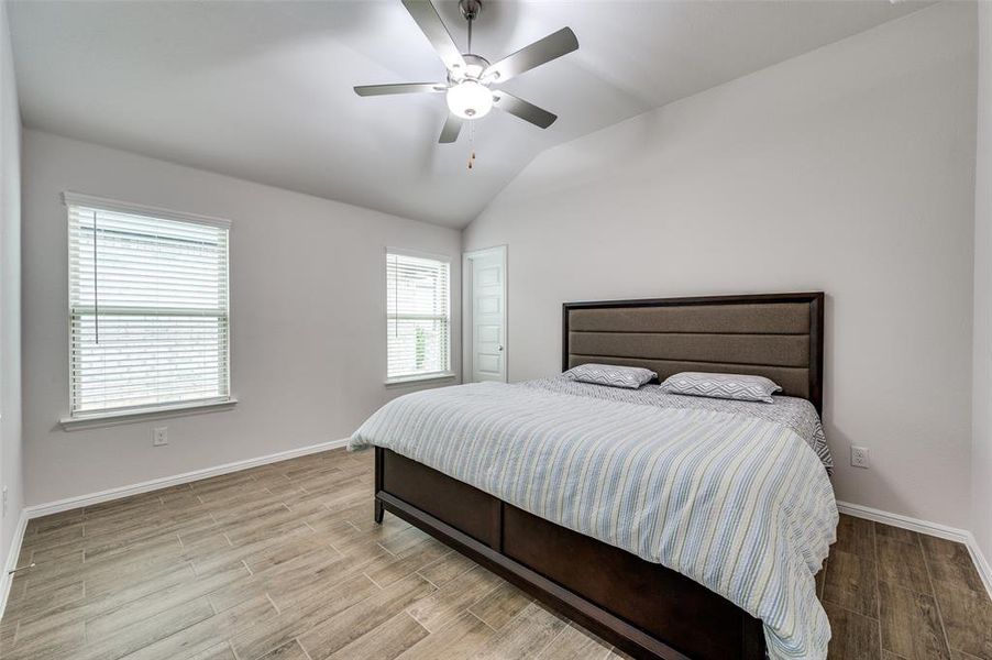 Bedroom with vaulted ceiling, ceiling fan, and light hardwood / wood-style floors