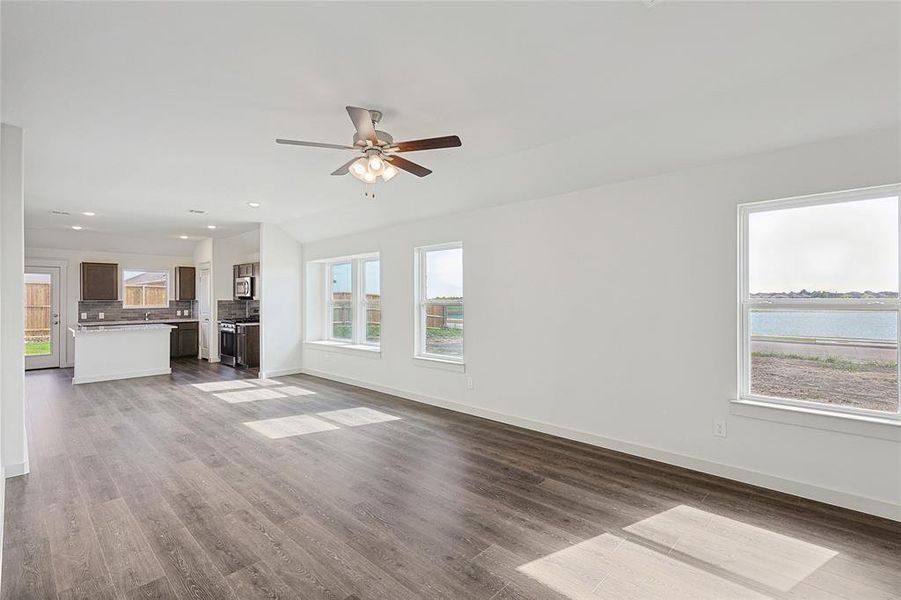 Unfurnished living room with a water view, ceiling fan, and wood-type flooring