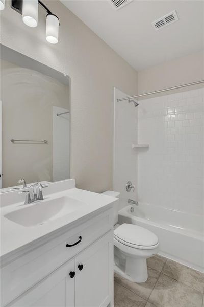 Full bathroom featuring vanity, toilet, tile patterned floors, and tiled shower / bath