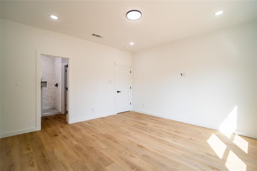 Unfurnished bedroom featuring a spacious closet and light hardwood / wood-style floors