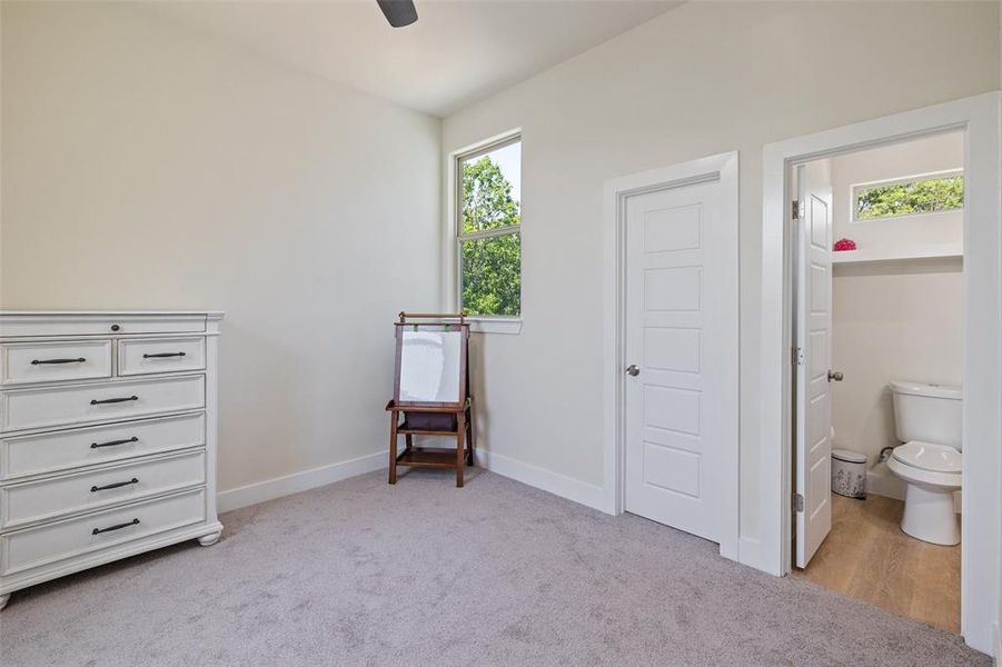 Upstairs bedroom with light colored carpet and ceiling fan