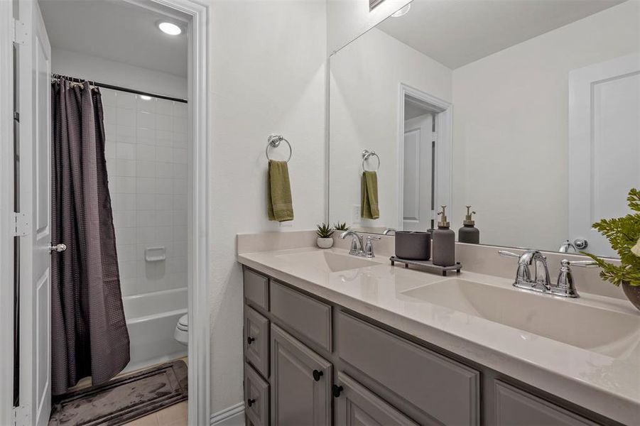 Full bathroom with tile patterned floors, double vanity, shower / tub combo, and toilet
