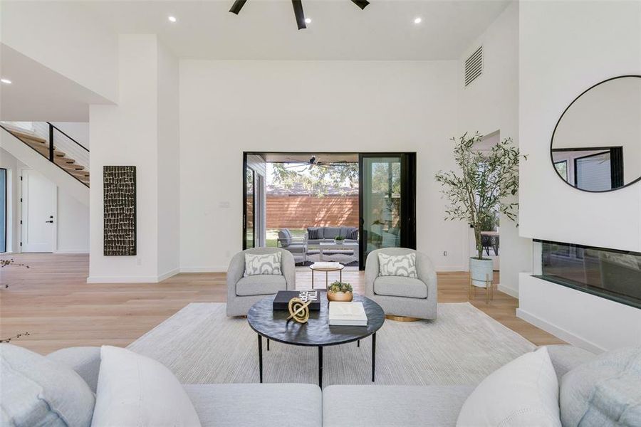 Living room featuring light hardwood / wood-style flooring, a high ceiling, and ceiling fan