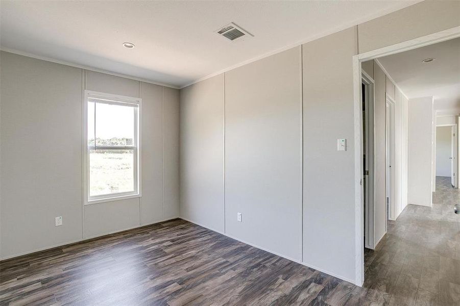 Spare room featuring crown molding and dark wood-type flooring