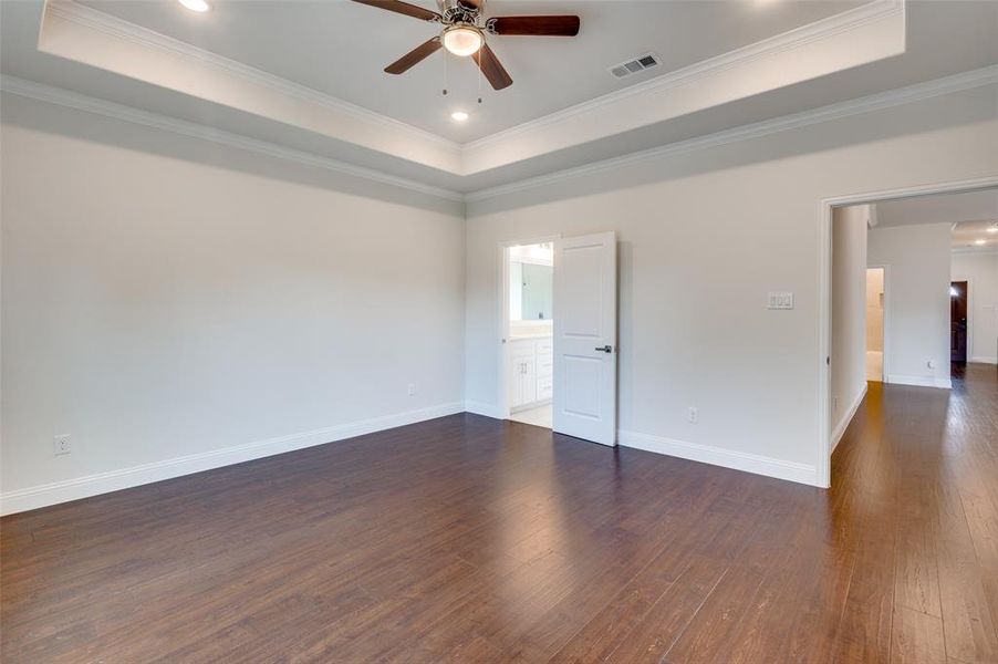 Unfurnished bedroom with hardwood / wood-style flooring, a raised ceiling, and ornamental molding