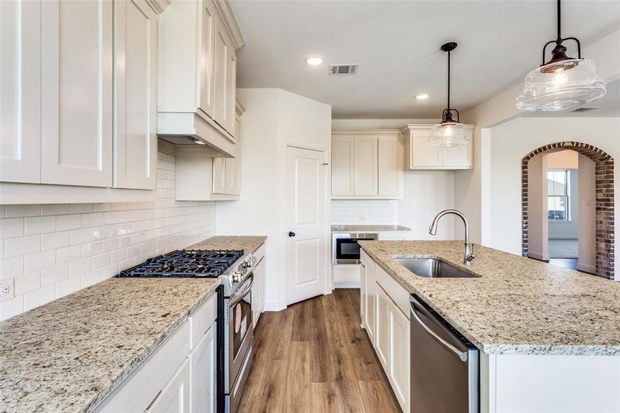 Kitchen featuring hanging light fixtures, sink, a center island with sink, stainless steel appliances, and light hardwood / wood-style floors