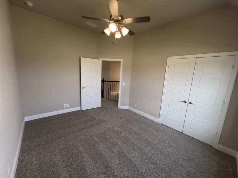 Unfurnished bedroom featuring dark colored carpet, a closet, and ceiling fan