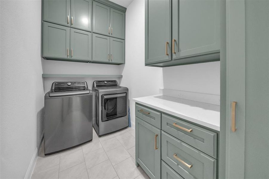 Laundry room featuring cabinets, light tile patterned flooring, and washer and clothes dryer