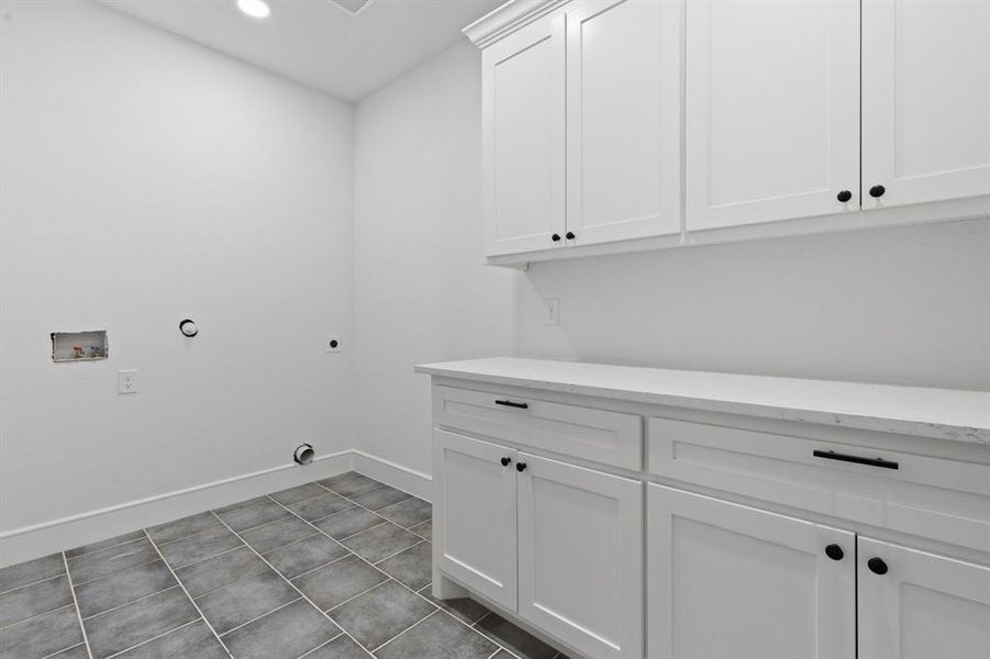 Laundry room featuring tile patterned flooring, hookup for an electric dryer, hookup for a washing machine, cabinets, and hookup for a gas dryer