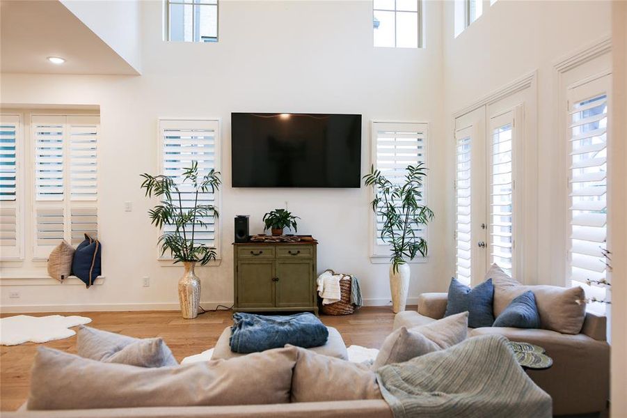 Living room featuring light hardwood / wood-style floors, a wealth of natural light, and a towering ceiling