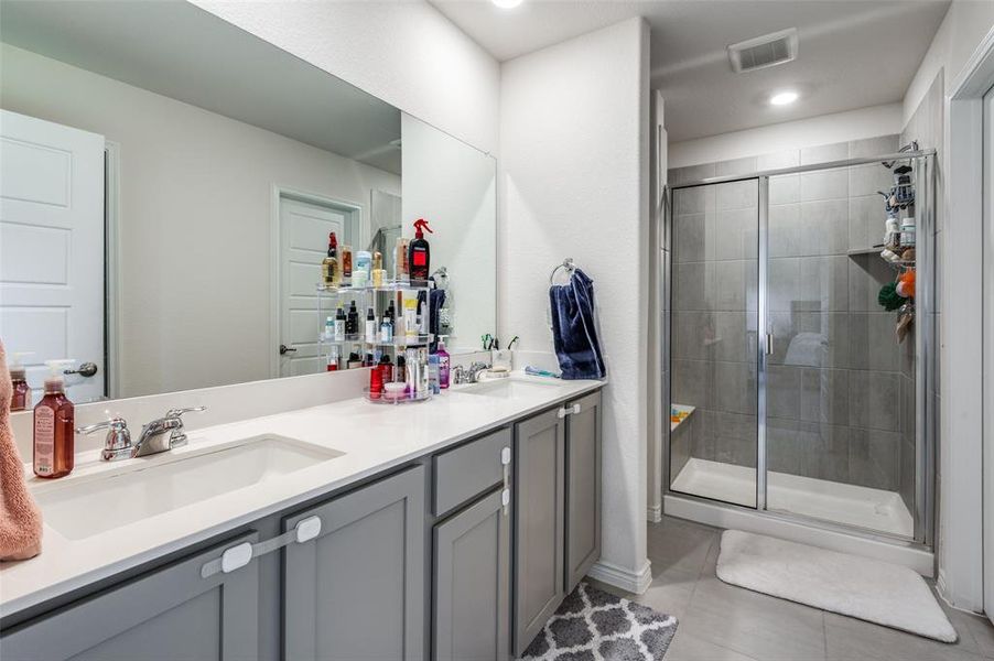 Bathroom featuring a shower with door, vanity, and tile patterned flooring