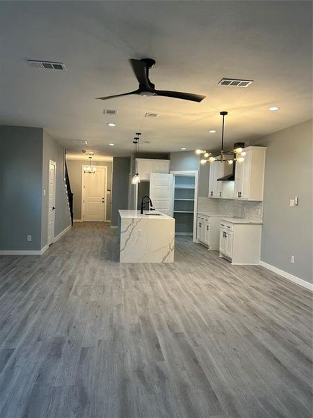 Kitchen featuring ceiling fan, decorative light fixtures, white cabinetry, and wood-type flooring
