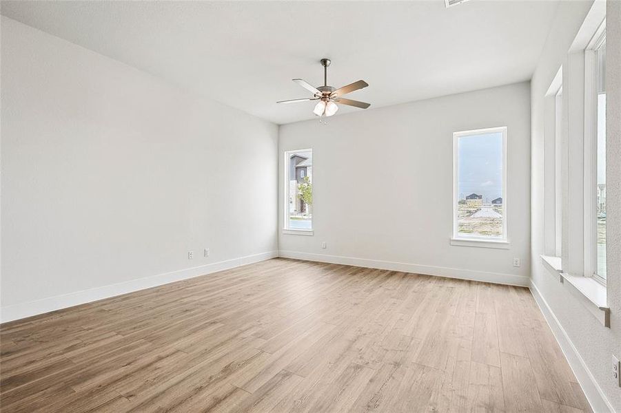 Empty room with ceiling fan, plenty of natural light, and light hardwood / wood-style floors