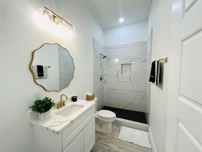 Bathroom with vanity, toilet, a tile shower, and hardwood / wood-style floors