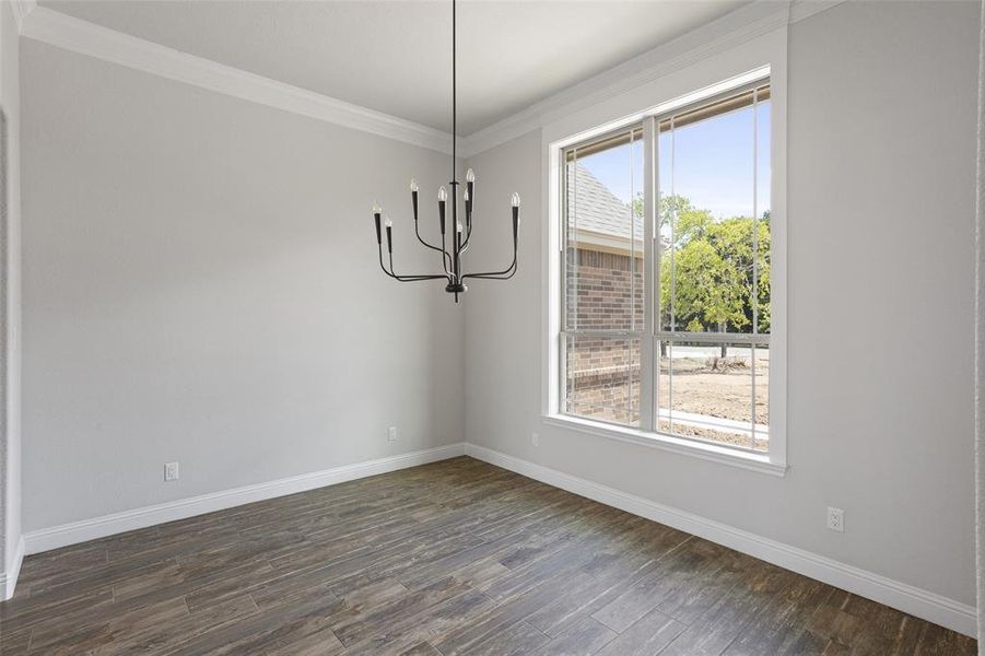 Empty room featuring an inviting chandelier, crown molding, and dark wood-type flooring