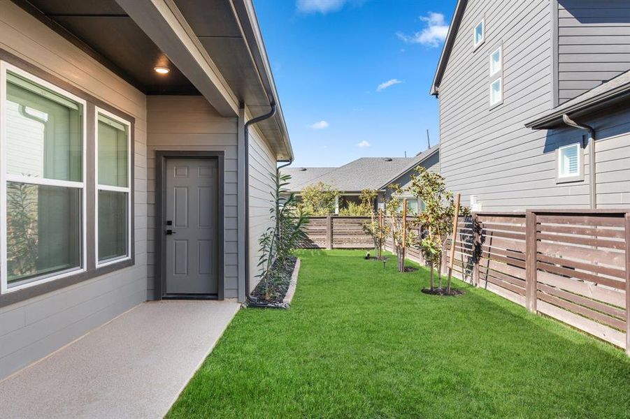 View of backyard and door to the three car garage from the back patio. *virtually enhanced lawn*