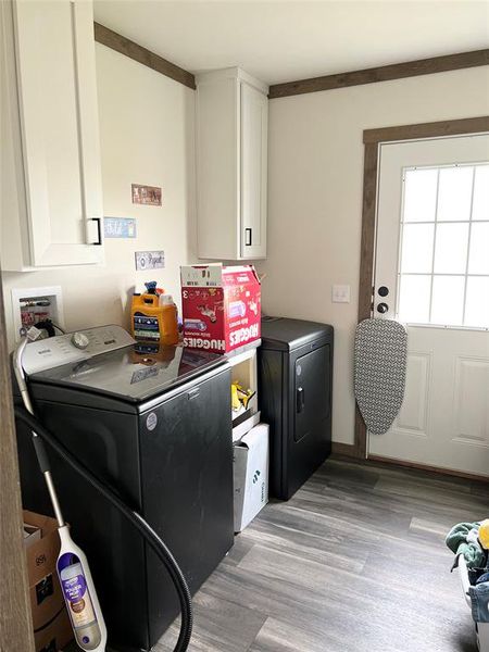 Washroom with light hardwood / wood-style floors, ornamental molding, cabinets, and washing machine and dryer