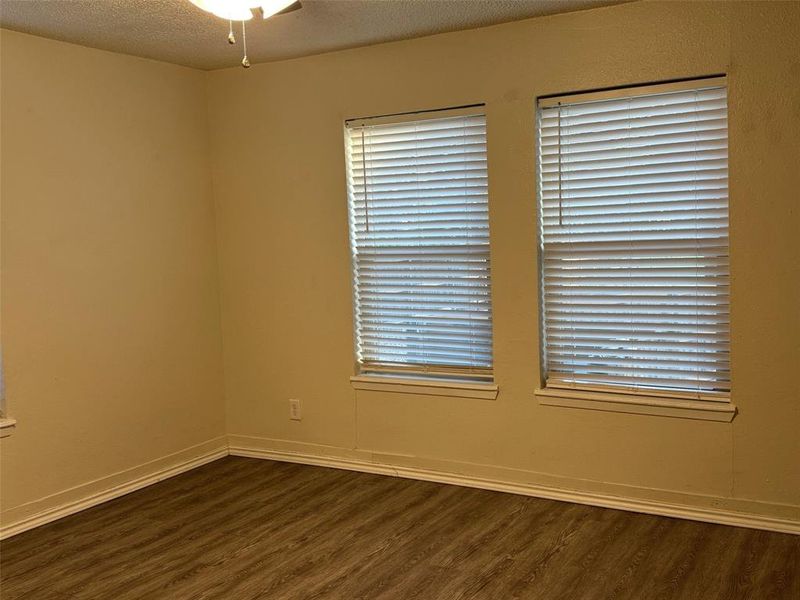 Empty room featuring ceiling fan, a textured ceiling, and dark hardwood / wood-style flooring